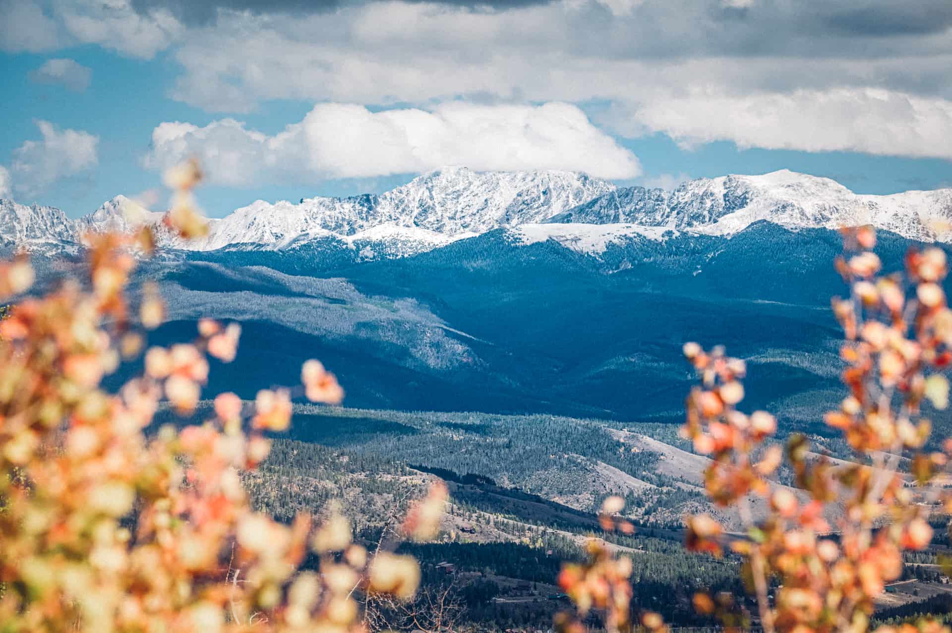 A view of a mountain range with snow capped mountains in the background.