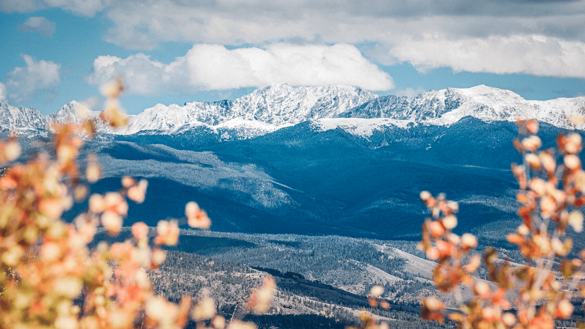 A view of a mountain range with snow capped mountains in the background.