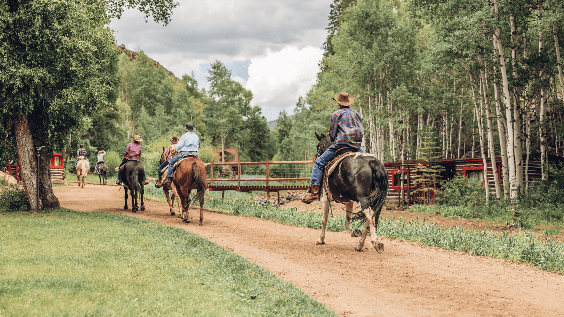 A group of people riding horses down a dirt road at Drowsy Water Ranch in Granby.