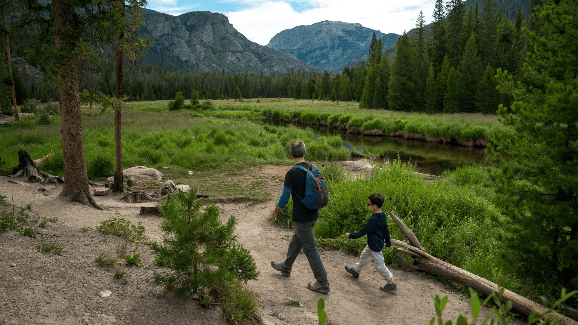 Two people walking along a trail in the mountains.