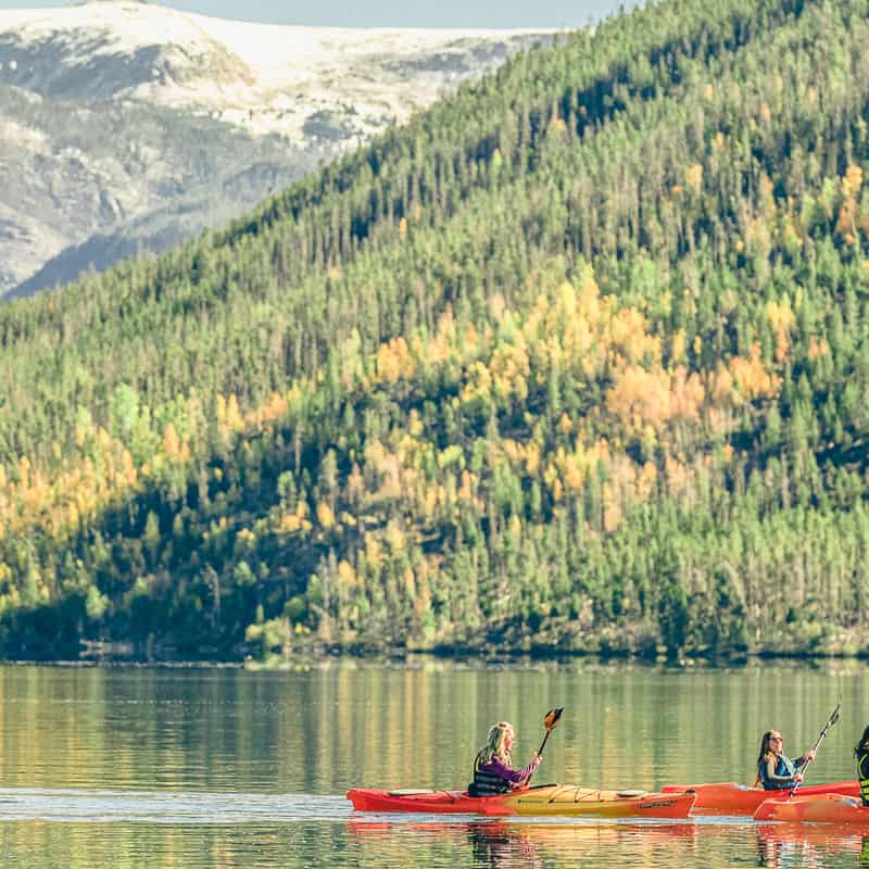 A group of people kayaking on a lake with mountains in the background.