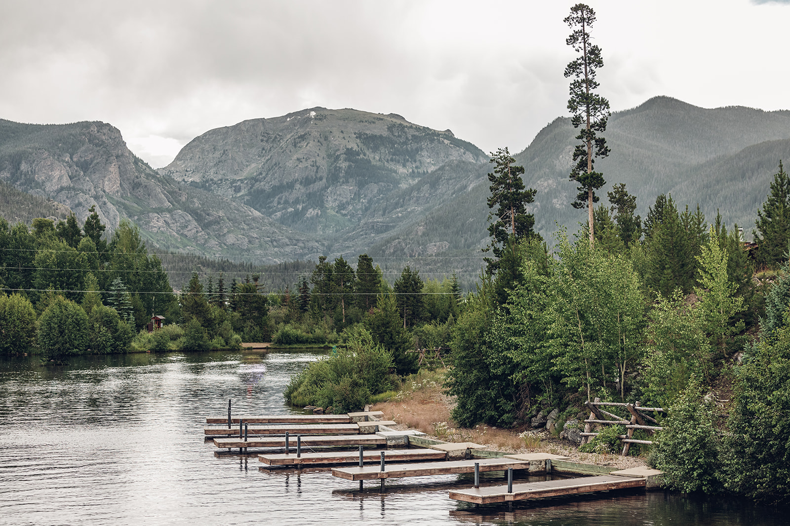 A lake with a dock and mountains in the background.