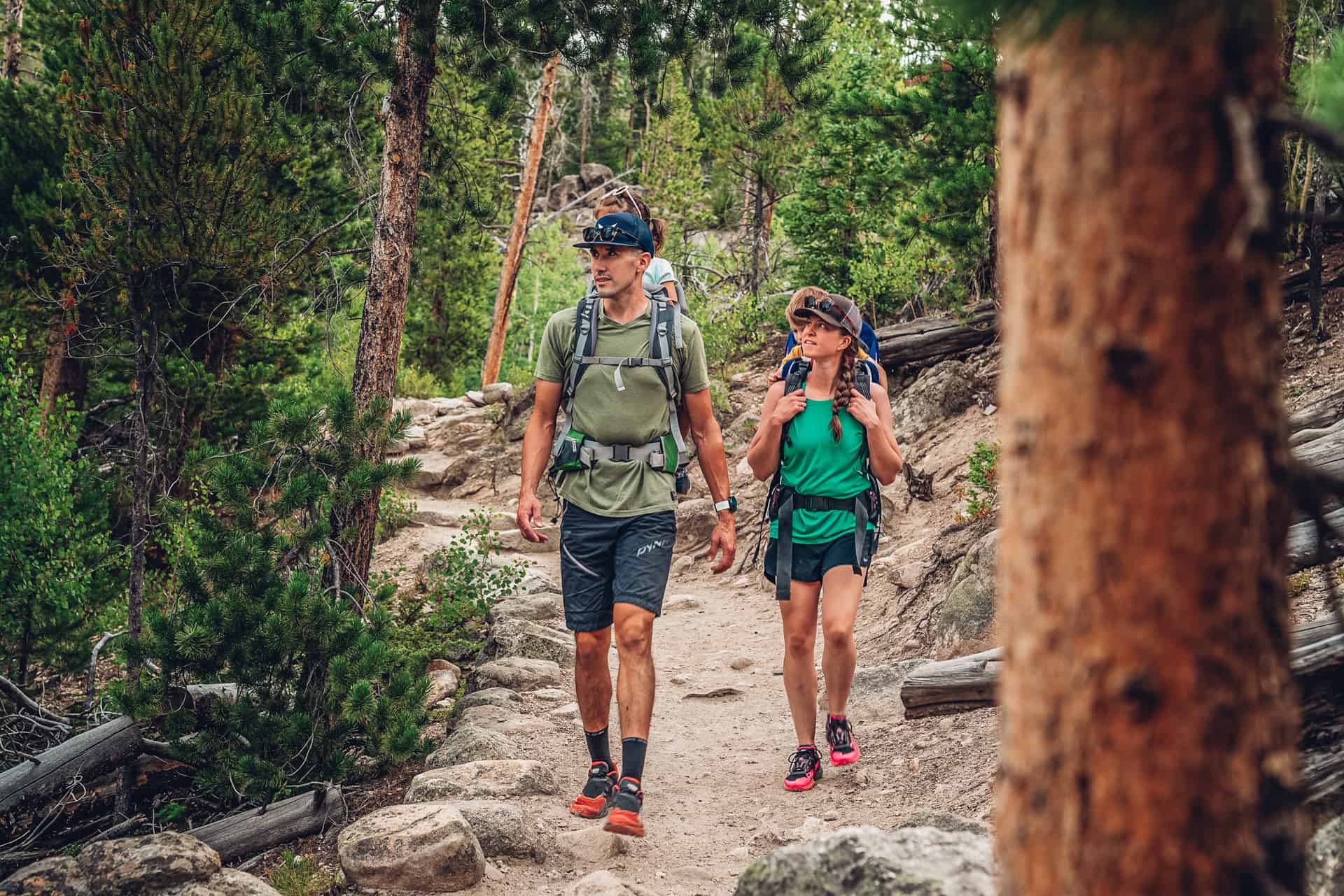 A man and woman hiking on a trail in the mountains.