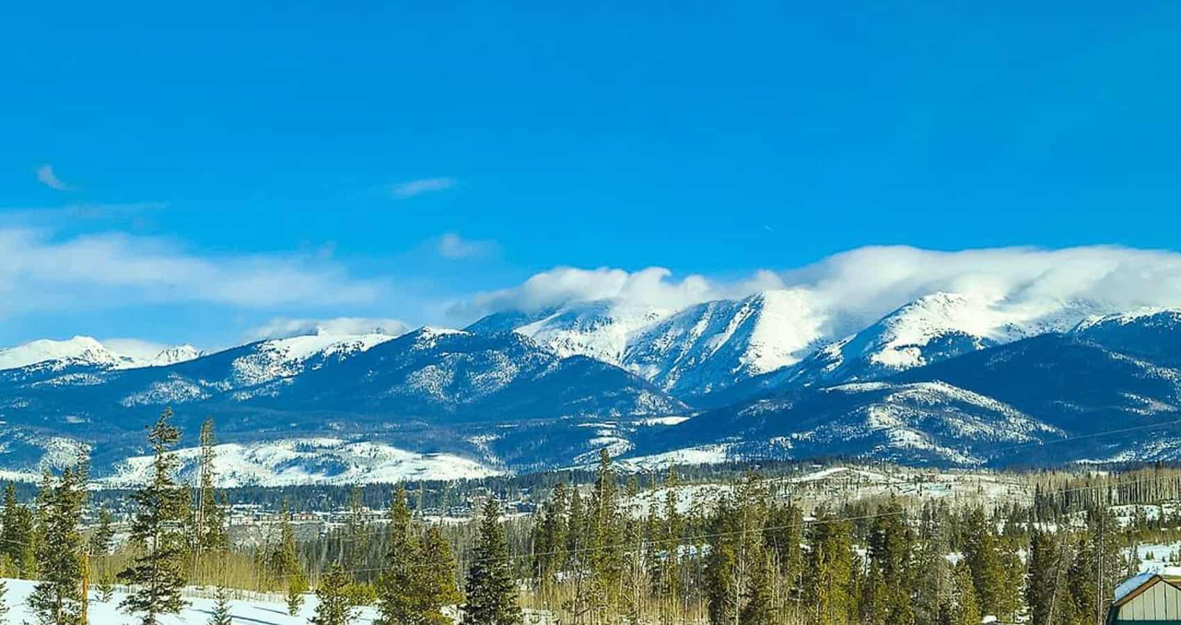 A snow covered mountain range with a house in the background.