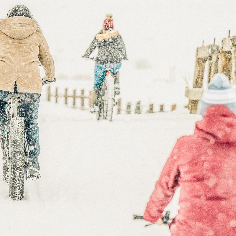 A group of people riding bikes in the snow.