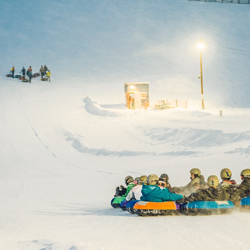 A group of people sledding down a hill.