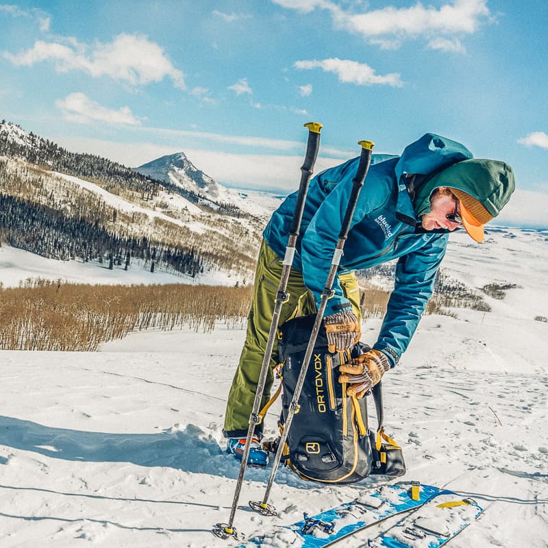 A man with skis and poles on a snowy slope.