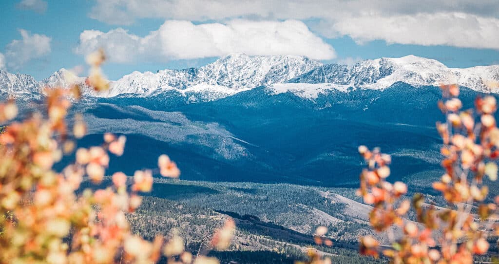 A view of a mountain range with snow capped mountains in the background.