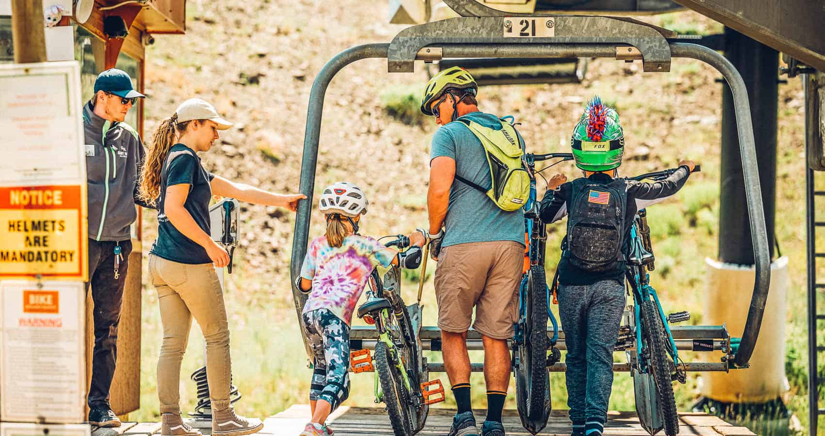 A group of people standing on a ski lift with their bikes.