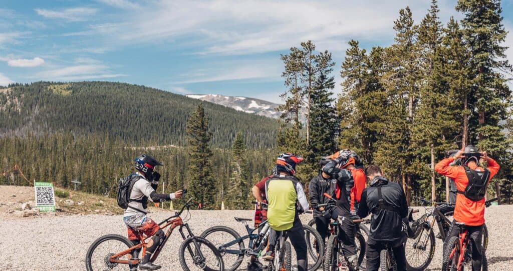 A group of mountain bikers standing in front of a mountain.