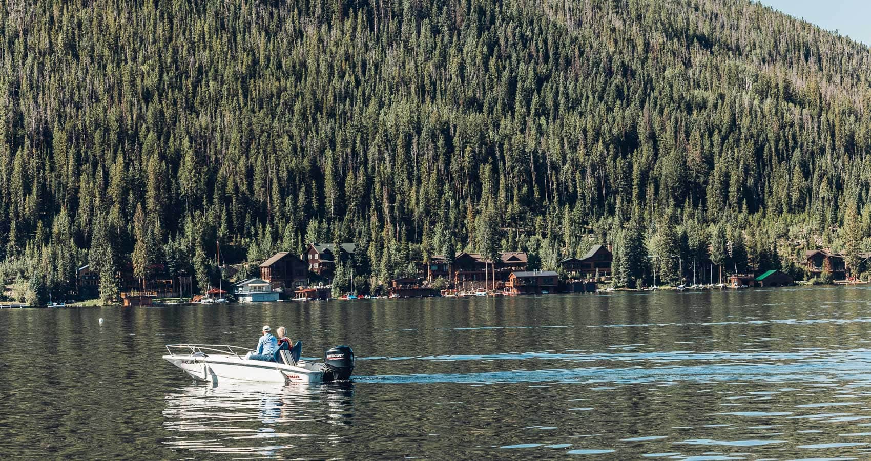 Two people on a boat in the middle of a lake.