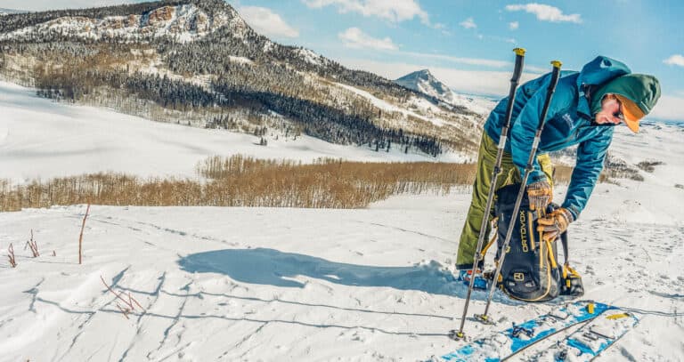 A man putting on his skis on a snowy slope.