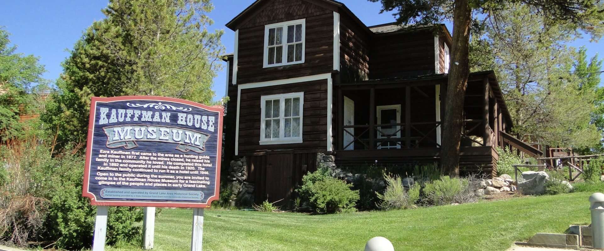 A wooden house with a sign in front of it.