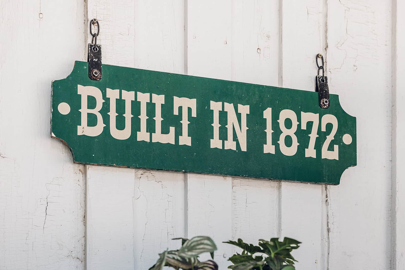 A green sign that says built in 1872 hanging on a wall.