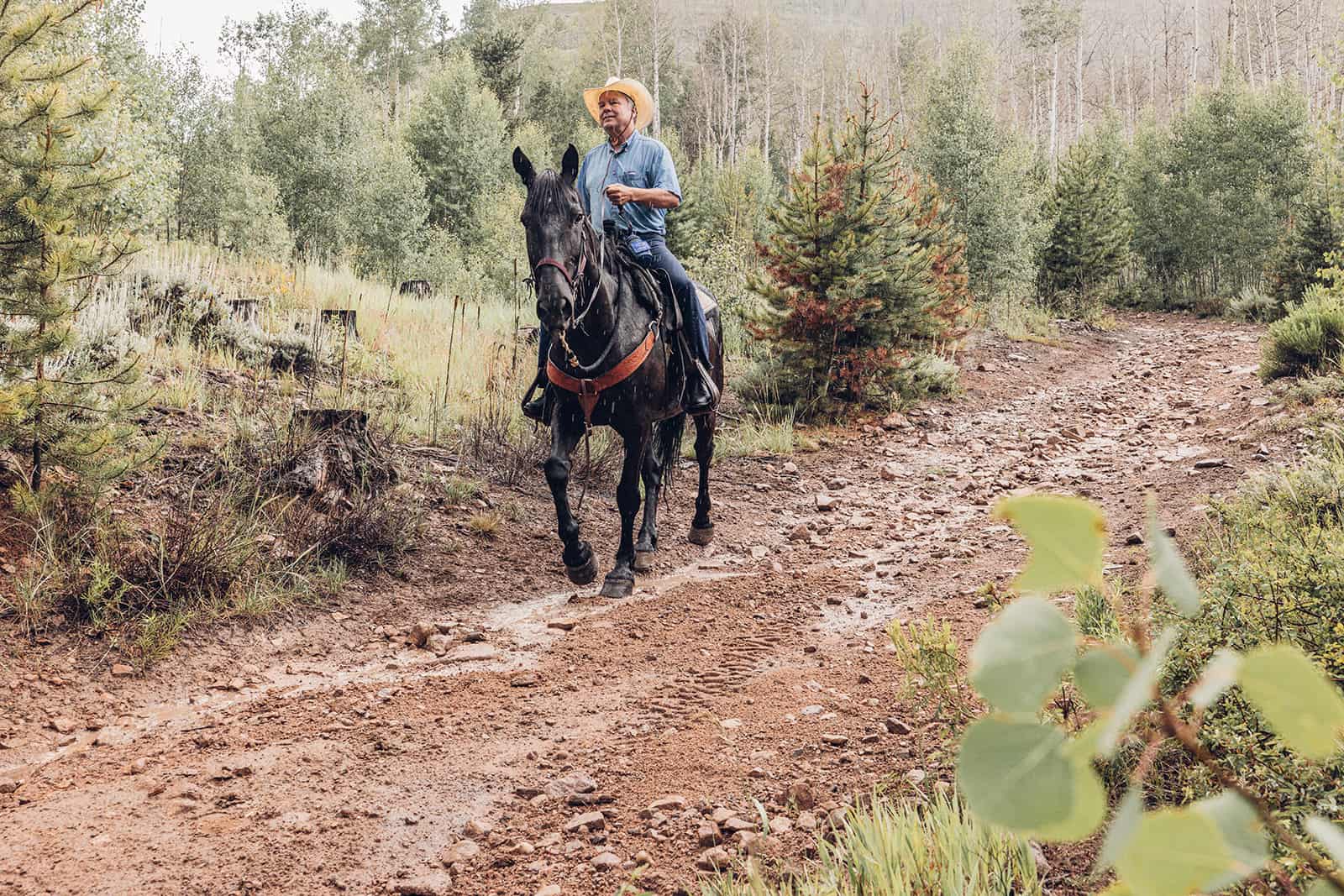 A woman riding a horse down a dirt road.