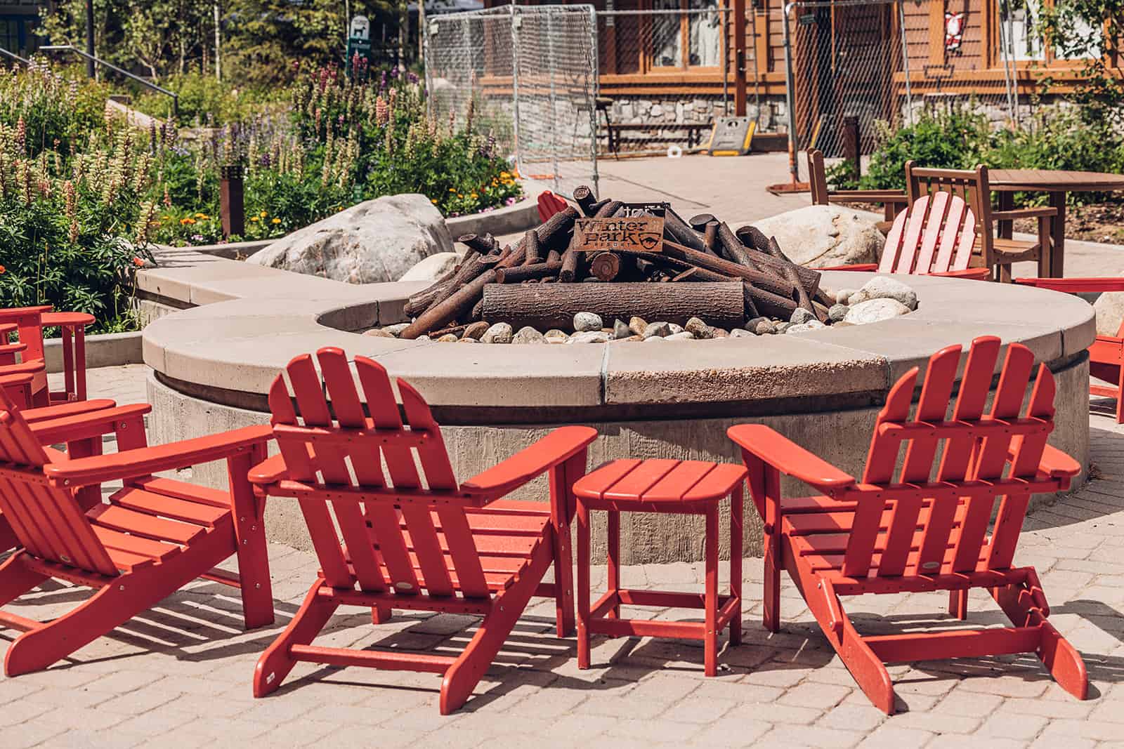 A group of red chairs around a fire pit.