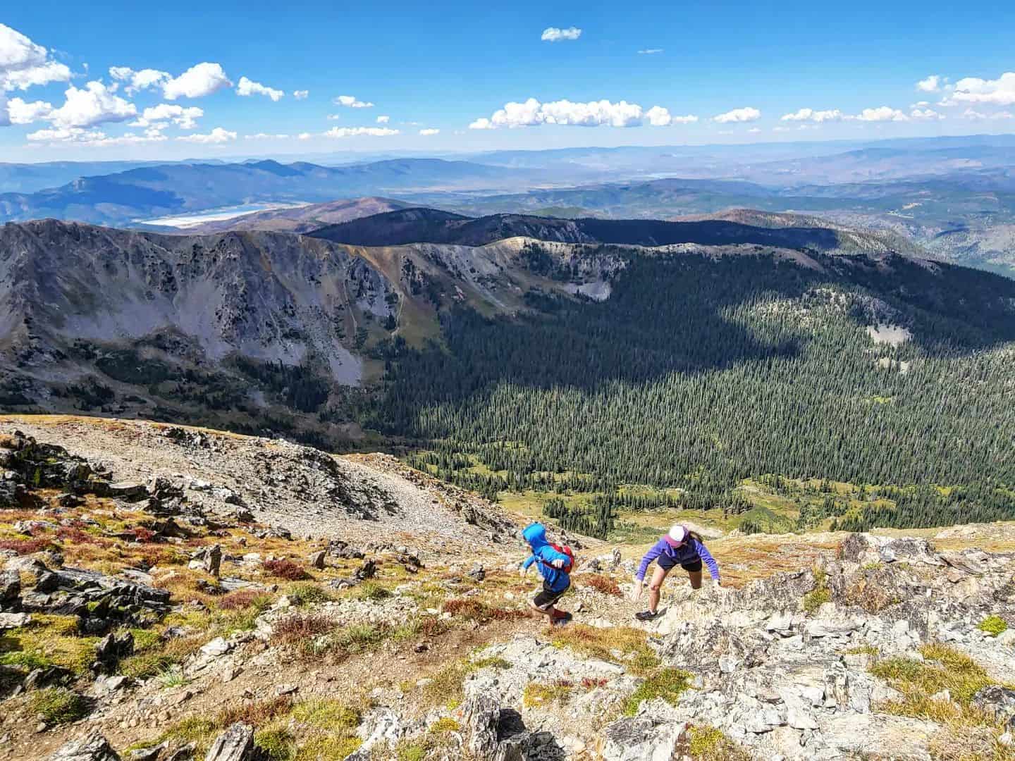 Two hikers on a rocky trail in the mountains.