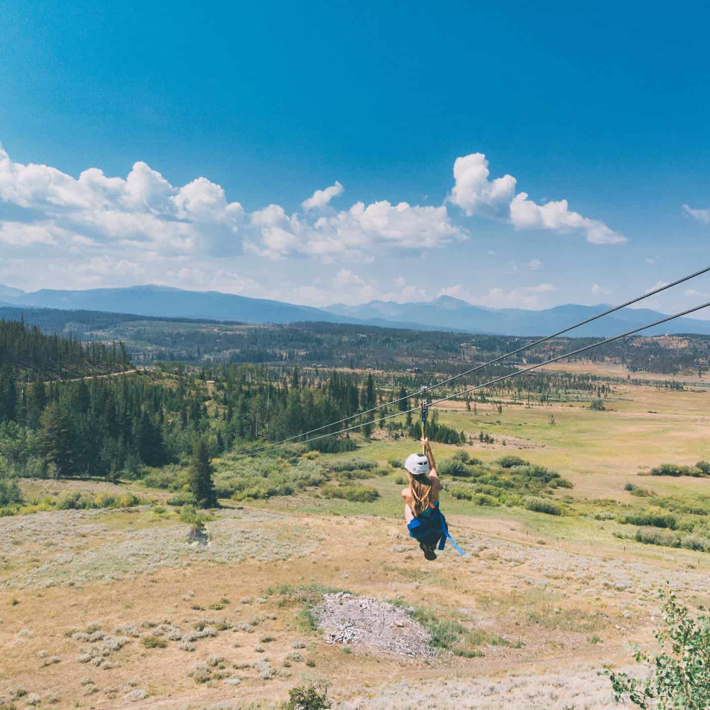 A person on a zip line in a grassy area.