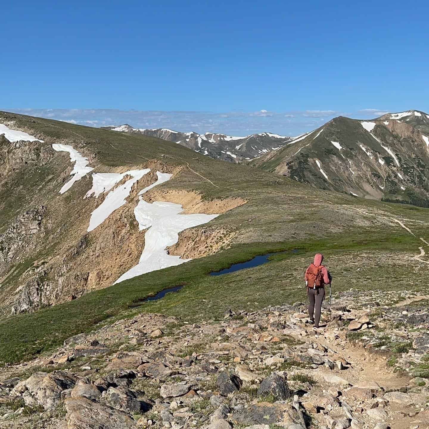 A hiker on a trail in the mountains.