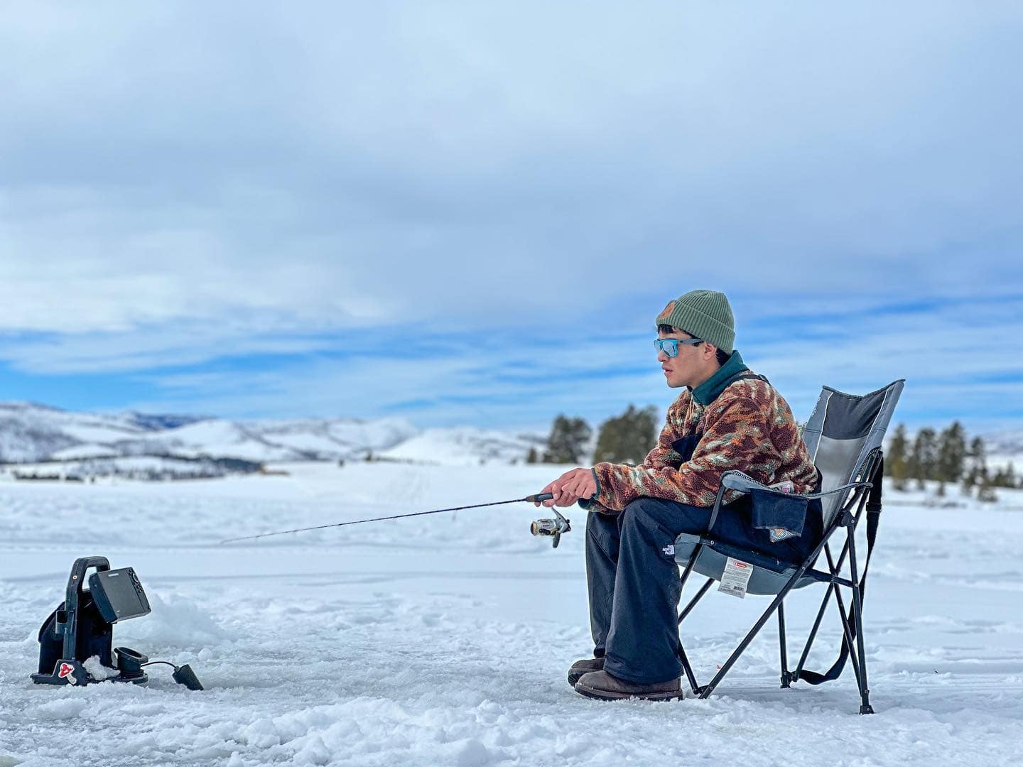 A man sitting in a chair on a frozen lake.