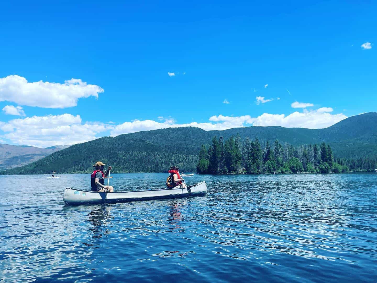 Two people paddling in a canoe on a lake.