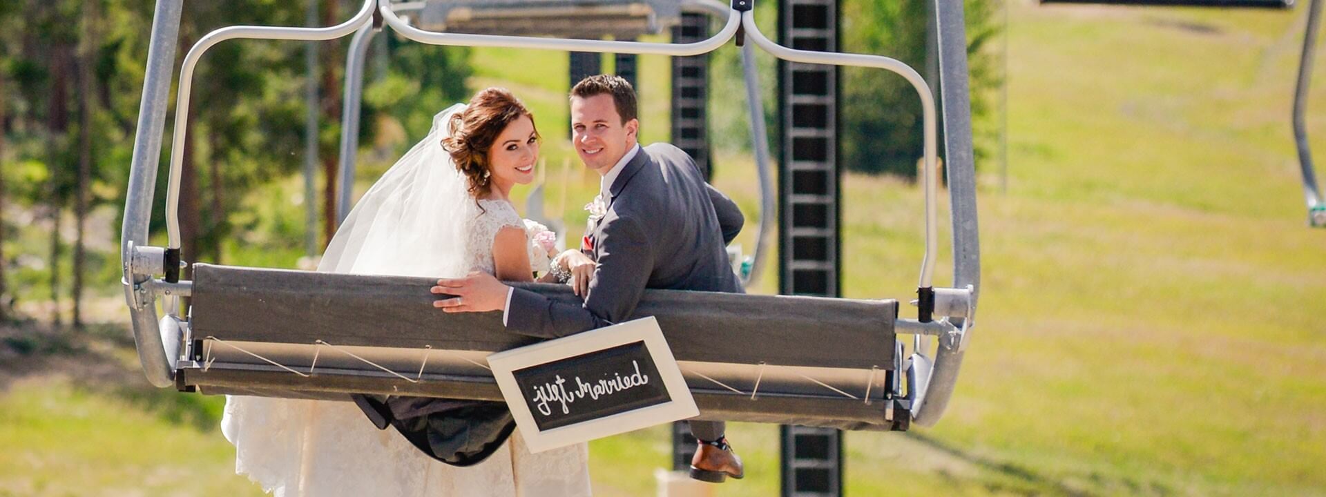 A bride and groom sitting on a ski lift.