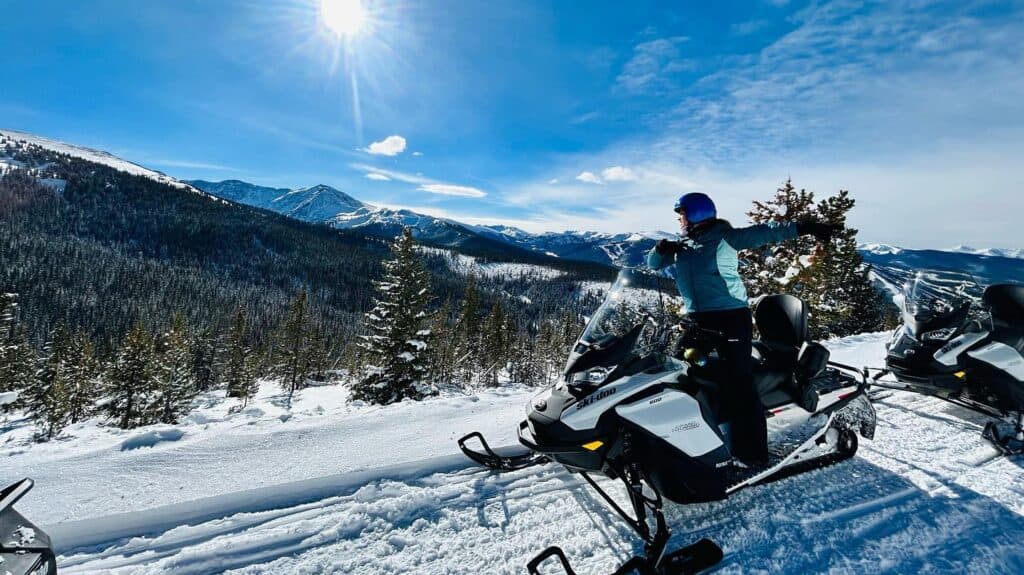 A group of people on snowmobiles on a snowy mountain.