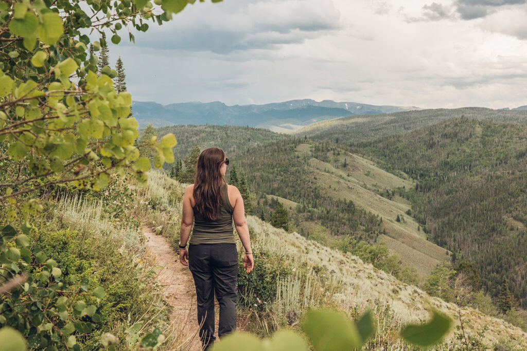 A woman walking down a trail in the mountains.