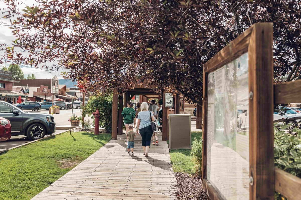 A group of people walking down a sidewalk surrounded by small shops in Grand Lake, Colorado.