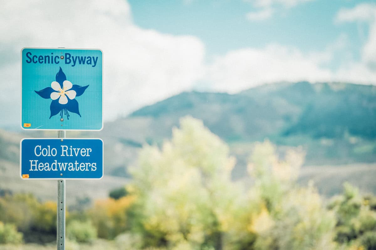 Colorado River Headwaters Scenic Byway sign in front of trees and mountains.