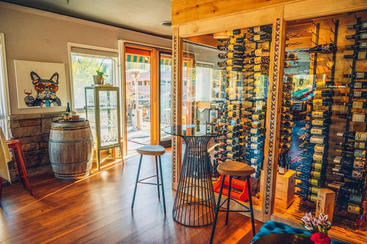 Interior of a winery restaurant in Winter Park with large displays of wine bottles with a table and large barrel.